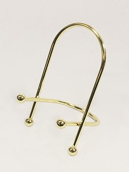 A brass easel in front of a beige background